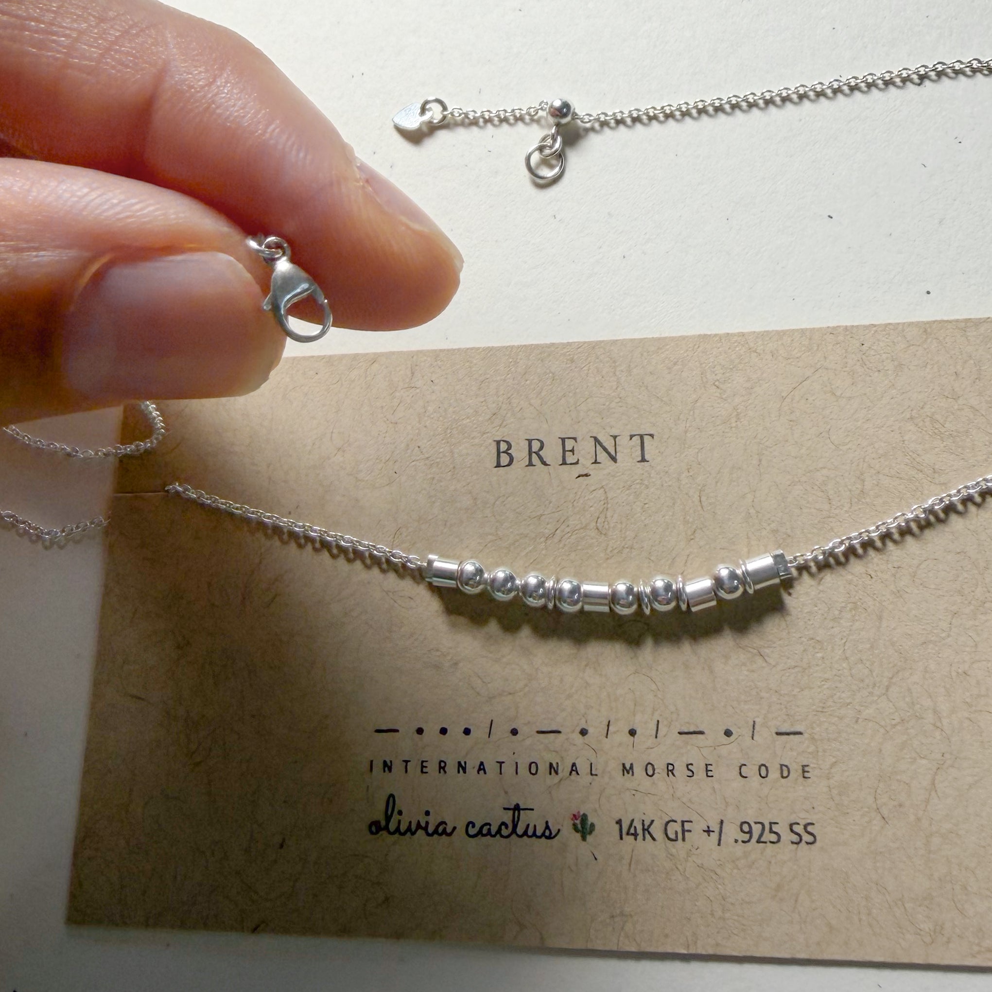 Lobster clasp and adjustable chain above the Extra Bold sterling silver Morse code necklace on its card