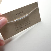 Angled view of the Extra Bold sterling silver Morse code necklace on its card, showing the round and tube beads