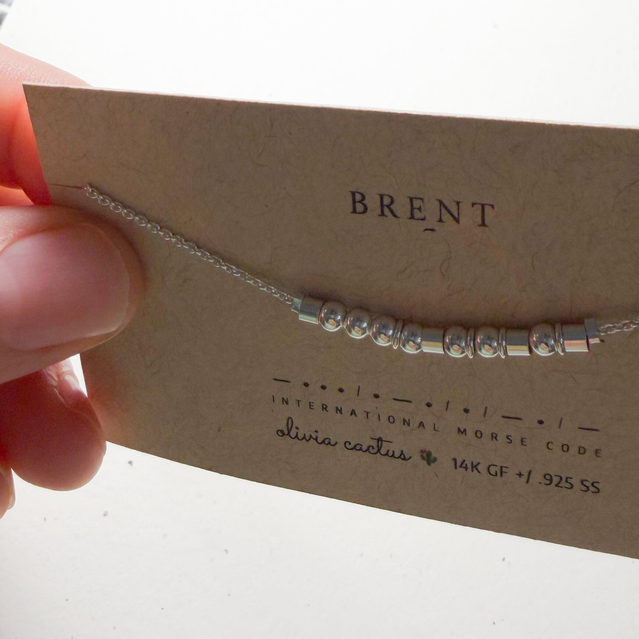Extra Bold sterling silver Morse code necklace on its card, held up at an angle