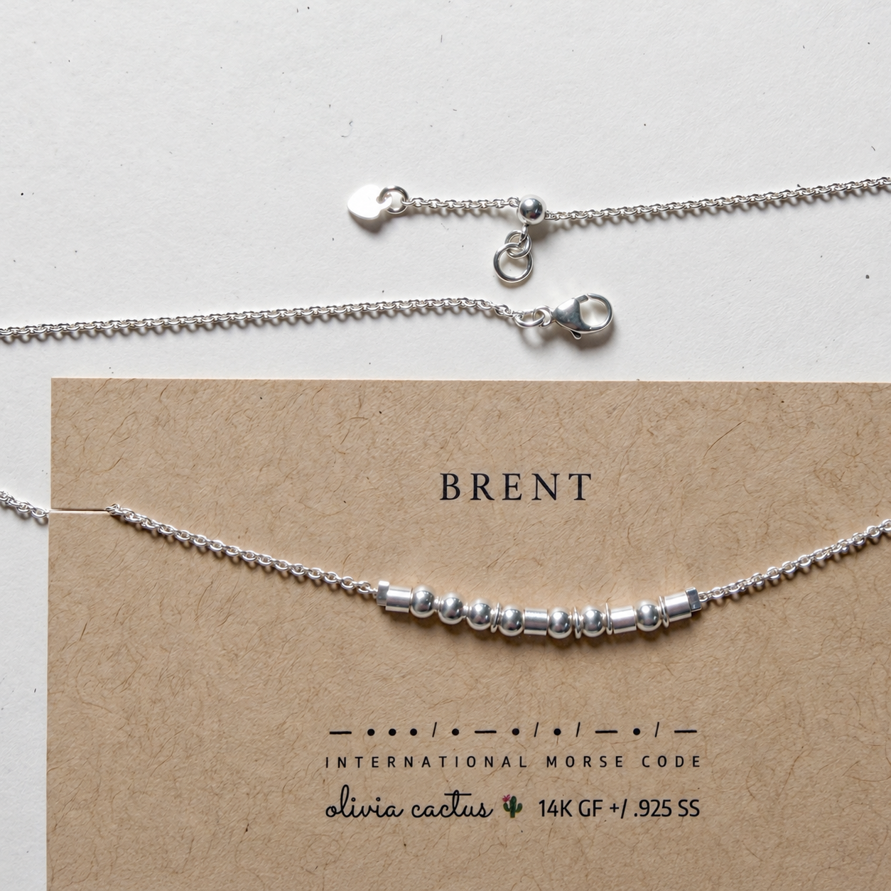 Extra Bold sterling silver Morse code necklace on its printed card, with the lobster clasp and adjustable slider shown above