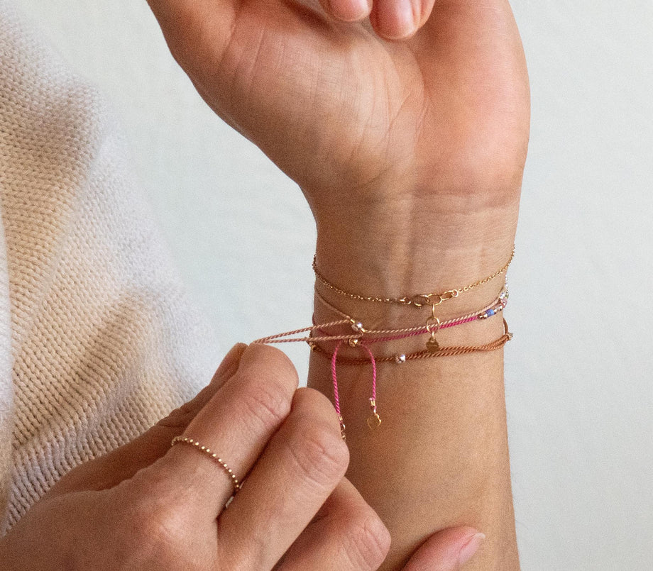 fingers pulling pink silk cord Morse code bracelets